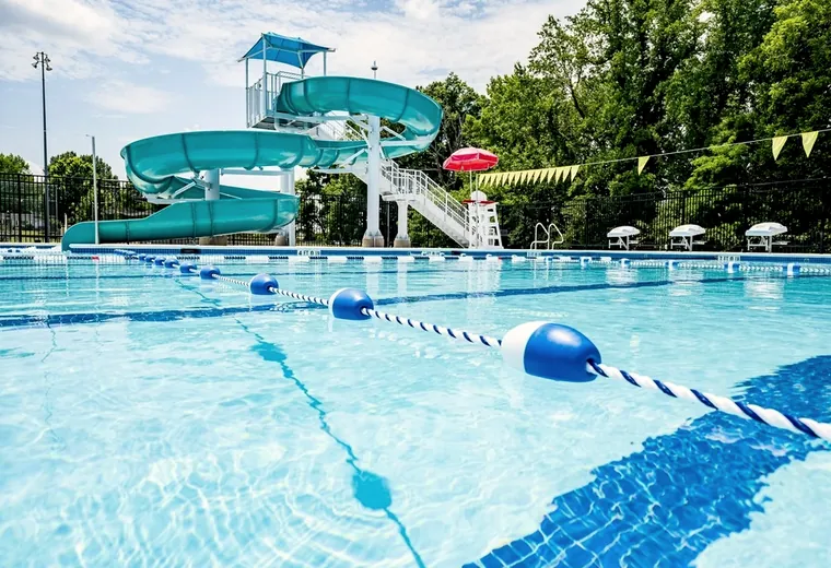 An outdoor pool with lane ropes and water slides