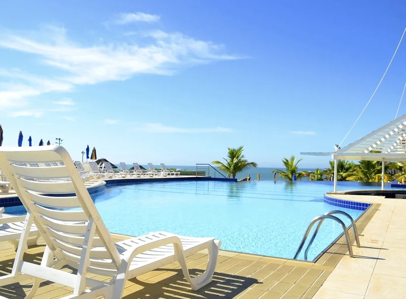 Sun loungers beside an outdoor pool with a sea view